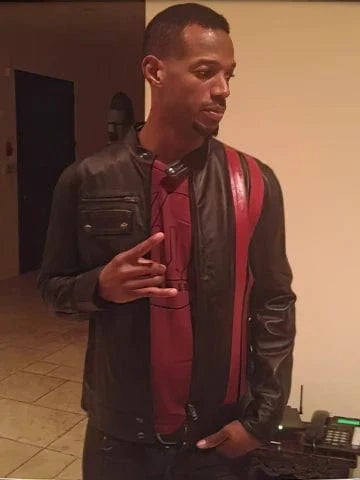 Marlon Wayans wearing slim fit black leather cafe racer jacket with red stripe detail indoors